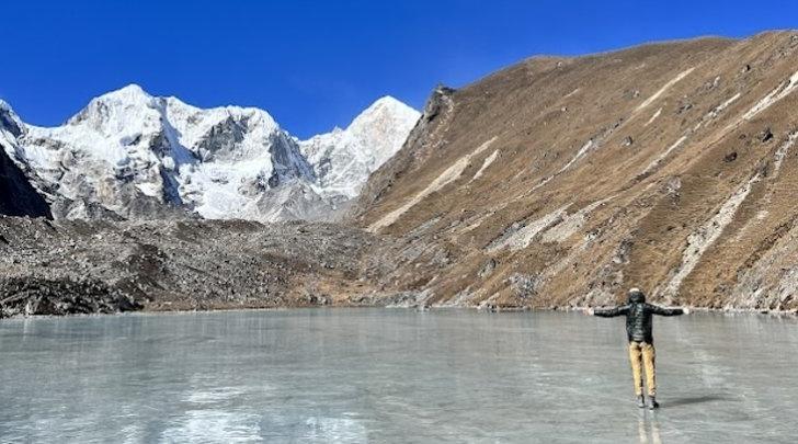 Student on sheet of ice in mountains of Nepal